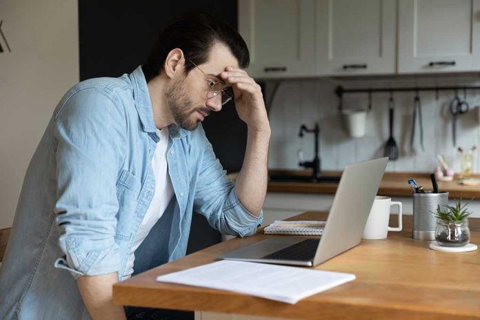 Man stressing over work on laptop at kitchen table
