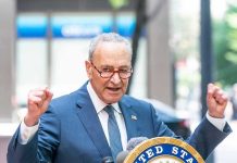 Man in suit and glasses speaks passionately at podium.