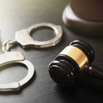Handcuffs and judge's gavel on the table