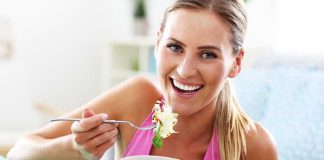Woman smiling and eating a salad bowl