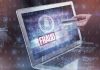 Person holding credit card near laptop displaying fraud