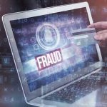 Person holding credit card near laptop displaying fraud