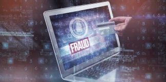 Person holding credit card near laptop displaying fraud