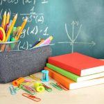 A collection of school supplies including notebooks, a pencil case, and writing instruments on a desk