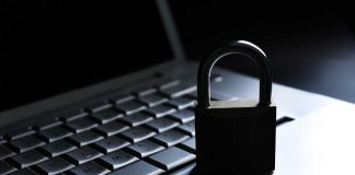 A padlock resting on a laptop keyboard in a dimly lit environment
