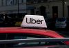 Uber sign on top of a red car in an urban setting