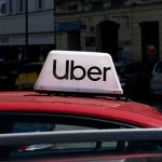 Uber sign on top of a red car in an urban setting
