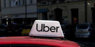 Uber sign on top of a red car in an urban setting