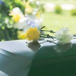 Yellow and white flowers on a green casket.