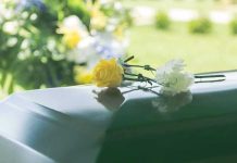 Yellow and white flowers on a green casket.