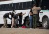 Border patrol officers investigating people near a bus.