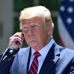 Trump FIRES Entire Dept—No Warning, No Mercy Man in a suit adjusting an earpiece.