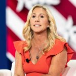 Woman speaking at an event, wearing a red dress.