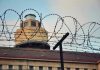 Barbed wire in front of a prison tower.