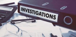 International MANHUNT Underway – Suspect Fled U.S! Documents and binder labeled Investigations on desk.