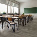 Democrat BRAINWASHING Scheme Uncovered – Infiltrated Schools! Empty classroom with desks, chairs, windows, and chalkboard.