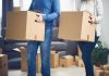 Exodus EXPOSED — Blue States Bleed Families Two people carrying cardboard boxes indoors.