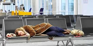 Air Traffic Chaos Looms — Controllers Issue Warning! A traveler sleeping on a bench in an airport waiting area