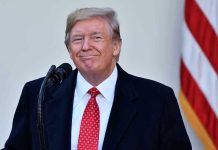 Trump WEAPONIZES G20 – Kicks South Africa OUT! Man in suit and tie speaking at podium.