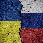 Cracked Ukrainian and Russian flags painted on concrete.