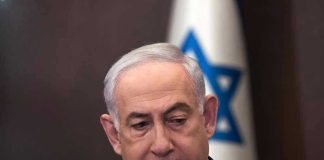 Netanyahu’s SHOCKING Reversal – Seeks Pardon Now Man in suit with Israeli flag in background.