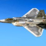 Fighter jet in flight against a clear blue sky.