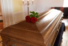 Wooden casket with red roses on top.