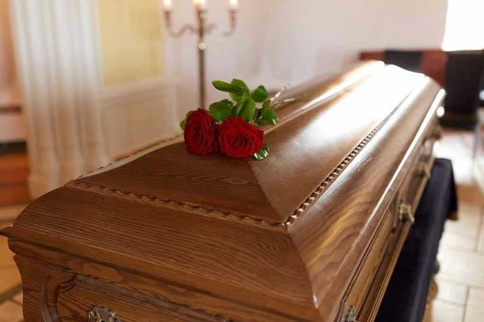 Wooden casket with red roses on top.