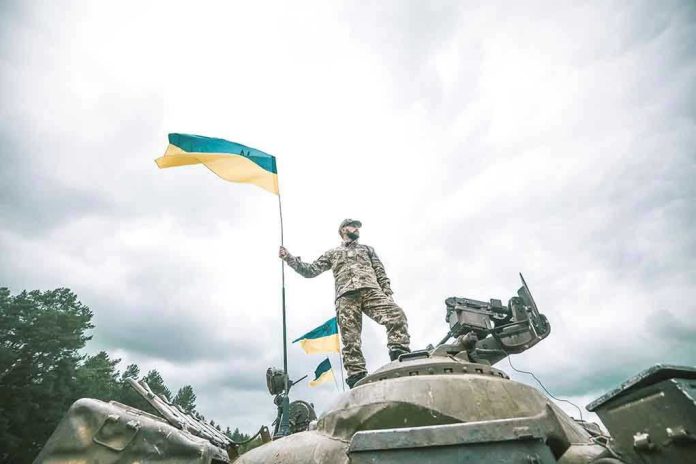 Soldier on tank holding Ukrainian flag.