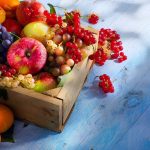 A wooden crate filled with a variety of fresh fruits including apples grapes and berries