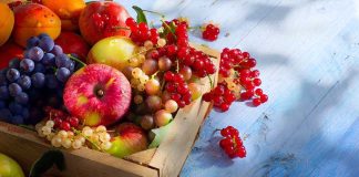 A wooden crate filled with a variety of fresh fruits including apples grapes and berries