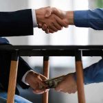 Handshake and exchange of money under the table.