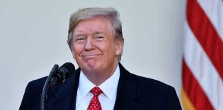 Trump’s Pardon’s Drug Lord – Let’s Him Walks Free Man in suit and tie speaking at podium.