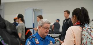 TSA Agent EXPOSES $18 Billion Cash Scheme TSA agent checks passengers documents at airport security.