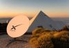 Satellite dish near pyramid-shaped building at sunset.