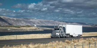 Truck driving on rural highway near river and mountains