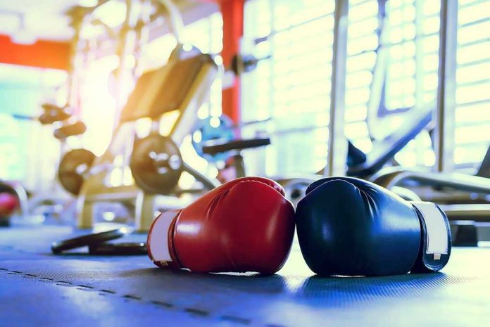 392673820 Boxing gloves on gym floor with equipment.