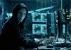 AI Hackers Outpace Humans — Nightmare Scenario Looms Person wearing mask and hoodie at computer desk.