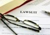 Lawsuit document with glasses, pen, and book.