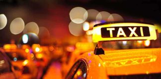 Robotaxi Chaos: Holiday Parade Nightmare Close-up of a taxi sign illuminated at night with blurred city lights in the background
