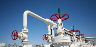 Industrial pipeline with red valves against a clear blue sky