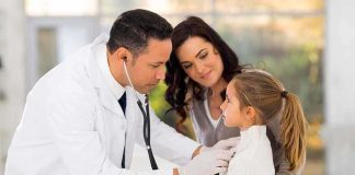 A doctor examines a young girl with a stethoscope while her mother watches