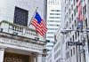Facade of the New York Stock Exchange with an American flag and Wall Street sign