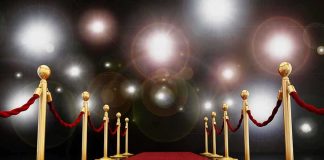 Hollywood Horror: Crimes Behind the Glitter A red carpet lined with gold stanchions and ropes under bright spotlights