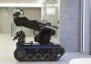 A robotic arm mounted on a tracked base in a modern workspace
