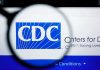 Shocking CDC Vaccine Cut: Experts Fear Disaster CDC logo magnified on a screen.