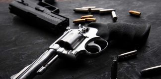 Gun Control Pushes On Despite Crime PLUMMET Revolvers and bullets on a dark surface.