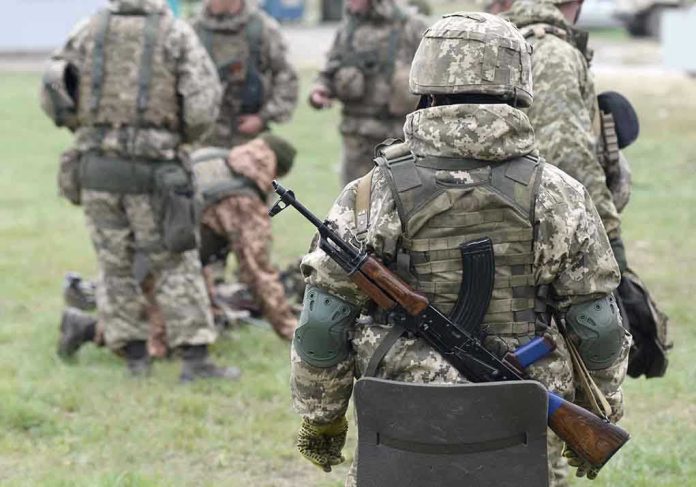 Soldiers in camouflage gear gathered on grass field.