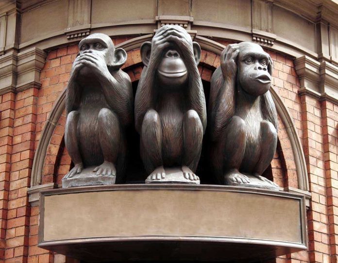 2749281 Three wise monkeys statue on a brick building.