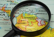 Trump’s Daring Venezuela Strike: What’s Next? Magnifying glass focusing on Venezuela and Colombia on map.